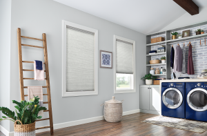 A modern laundry room with wood flooring and cellular shades on the windows.