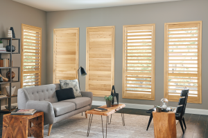 An elegant living room has windows with light wood plantation shutters.